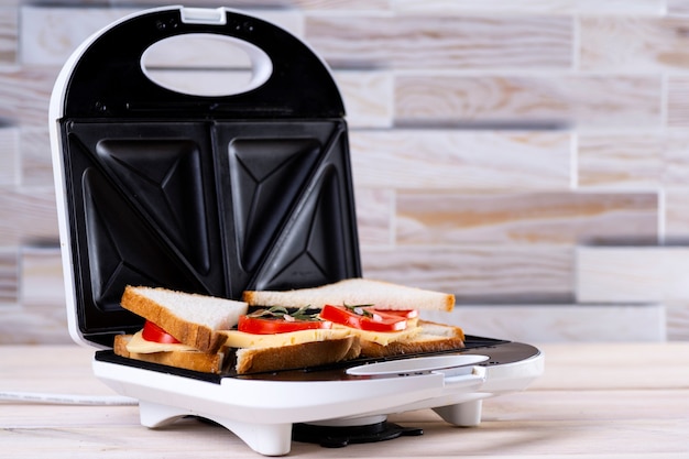 Hacer sándwiches de queso y tomate en una prensa para sándwiches