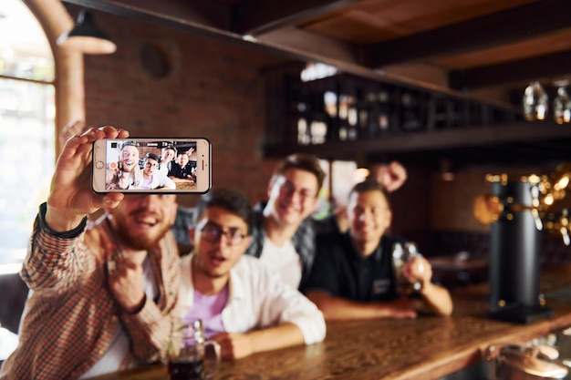 Hacer selfie Gente con ropa informal sentada en el pub