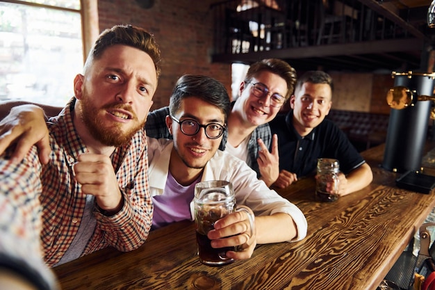 Hacer selfie Gente con ropa informal sentada en el pub