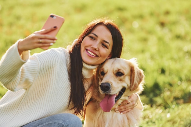 Hacer selfie Mujer joven dar un paseo con Golden Retriever en el parque