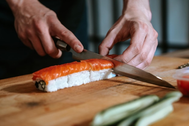 Hacer sushi y rollos en casa Primer plano de la mano de un hombre