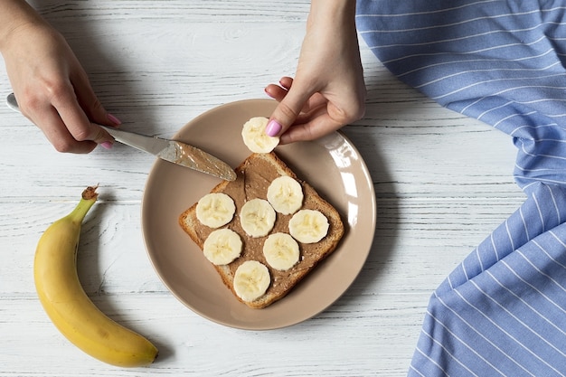 Foto hacer tostadas de pan blanco para el desayuno americano con mantequilla de maní y rodajas de plátano