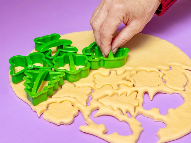 Haciendo galletas en forma de varias figuras. Mujer pastelera con la ayuda de moldes de plástico se forma a partir de la masa de galletas para hornear