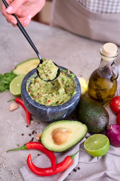 Haciendo guacamole mujer sosteniendo una cuchara con ingredientes picados mixtos