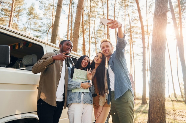 Haciendo selfie Grupo de jóvenes viajan juntos en el bosque durante el día