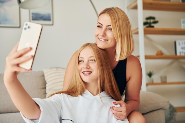 Haciendo selfie Mujer adolescente con su madre está en casa durante el día