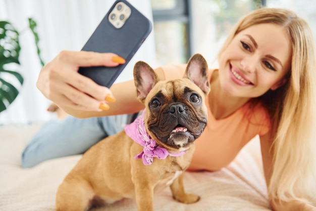 Haciendo selfie Mujer con perro pug está en casa durante el día