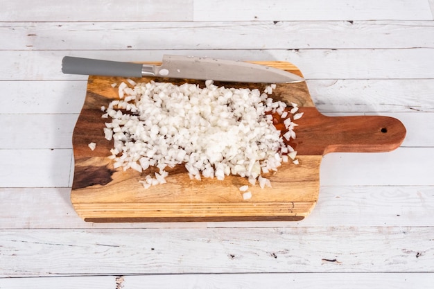 Hacken von organischen gelben Zwiebeln auf einem Holzschneidebrett.