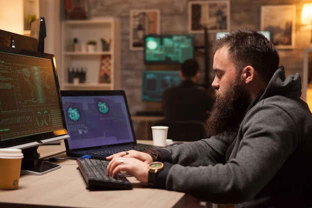 Hacker adulto escribiendo un virus en la computadora para romper la seguridad del firewall. Hacker joven en el fondo.