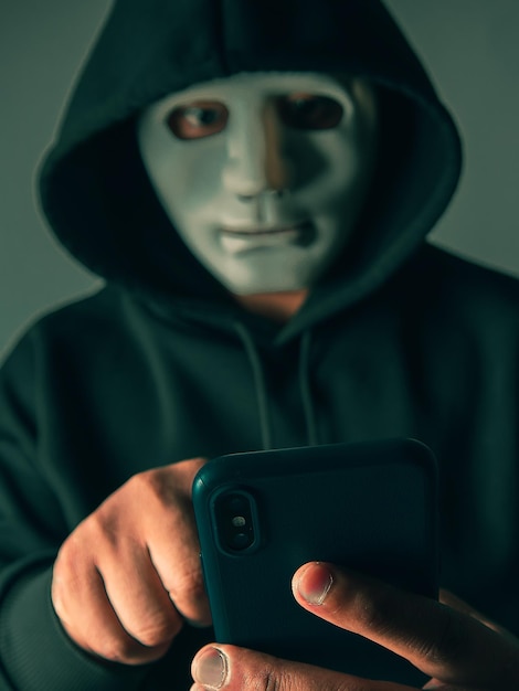 El hacker anónimo enmascarado está utilizando teléfonos inteligentes para penetrar la información financiera de la tarjeta de crédito Concepto de piratería y malware