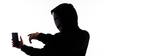 Hacker Anonymous und Gesichtsmaske mit Smartphone in der Hand