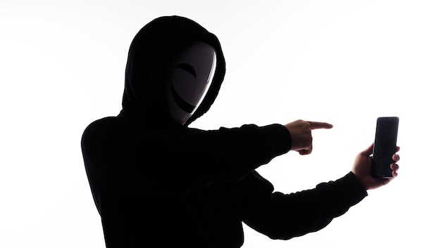 Hacker Anonymous und Gesichtsmaske mit Smartphone in der Hand