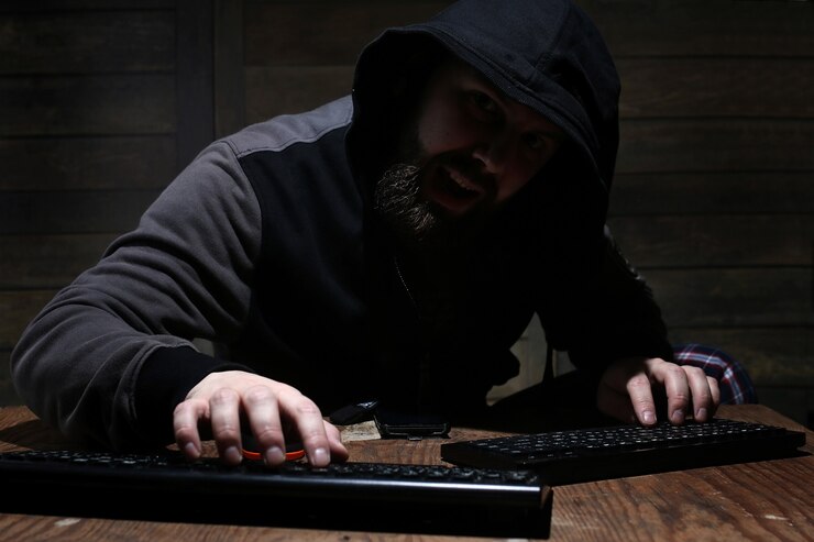Foto hacker en el capó negro en una habitación con paredes de madera.