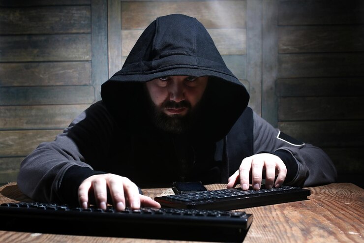 Foto hacker en el capó negro en una habitación con paredes de madera.
