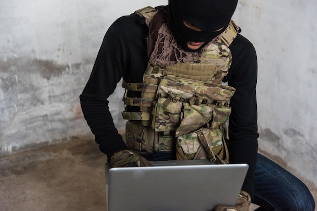 Hacker cibernético de homem terrorista hackeando a Internet para acessar informações roubadas por laptop, conceito criminoso de ladrão