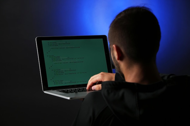 Hacker con computadora y laptop sobre fondo oscuro colorido