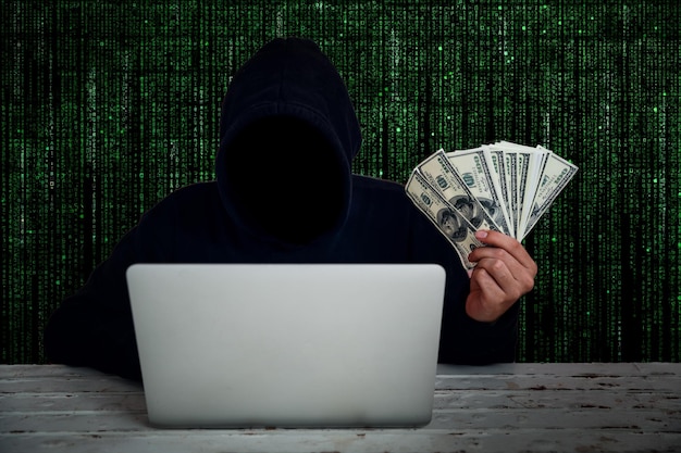 Foto hacker de computador segurando moeda de papel enquanto usa laptop