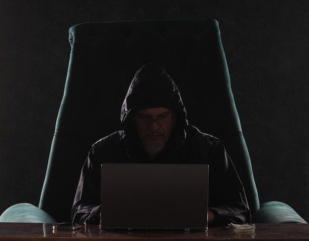hacker encapuchado con laptop