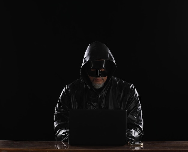 hacker encapuchado con laptop