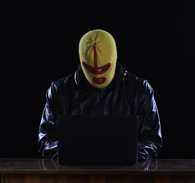 hacker encapuchado con laptop