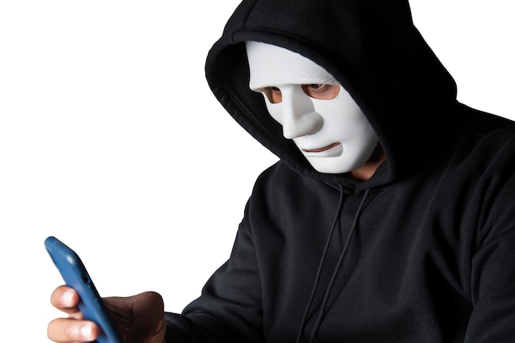 Foto un hacker enmascarado anónimo está utilizando teléfonos inteligentes para penetrar datos financieros con el concepto de malware y piratería de ruta de recorte