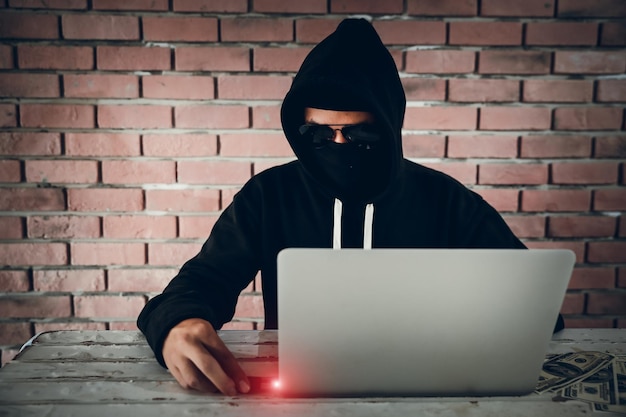 Hacker enquanto usa laptop na mesa