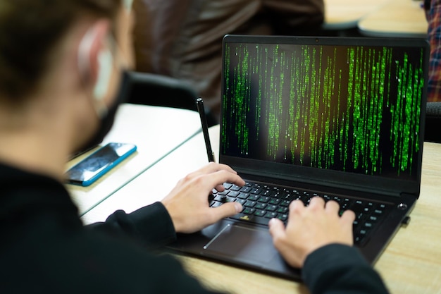 Hacker escribe código en la computadora portátil en estilo matriz