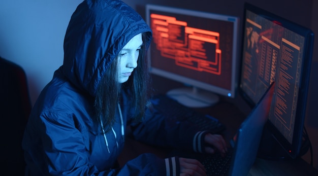 Hacker femenina en una sudadera con capucha atacando una base de datos