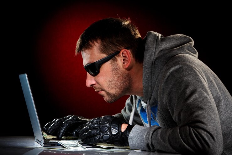 Foto hacker en gafas de sol con portátil.