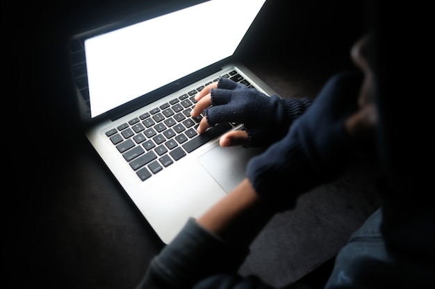 Hacker Hand stiehlt Daten vom Laptop von oben nach unten.