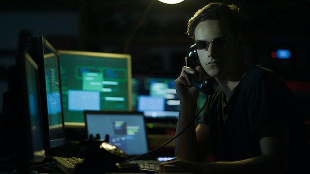 Hacker hoding un receptor y pantallas de computadora
