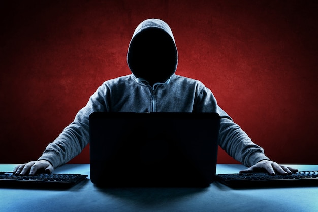 Hacker imprime um código em um teclado de laptop para invadir um ciberespaço