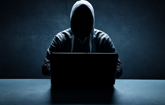 Hacker imprime um código em um teclado de laptop para invadir um ciberespaço