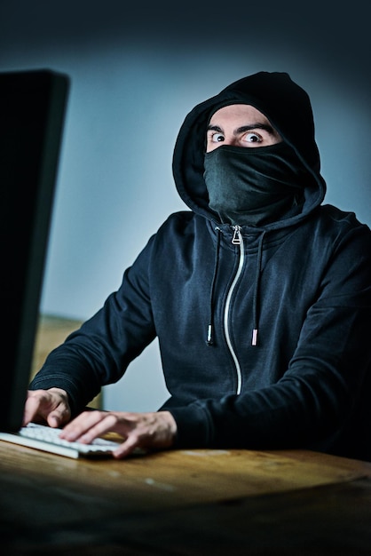 Hacker informático y retrato de hombre por la noche para ciberataque fraude y estafa digital en el hogar Crimen de ciberseguridad y persona masculina con tecnología por la mesa para codificación de riesgo de privacidad y ransomware