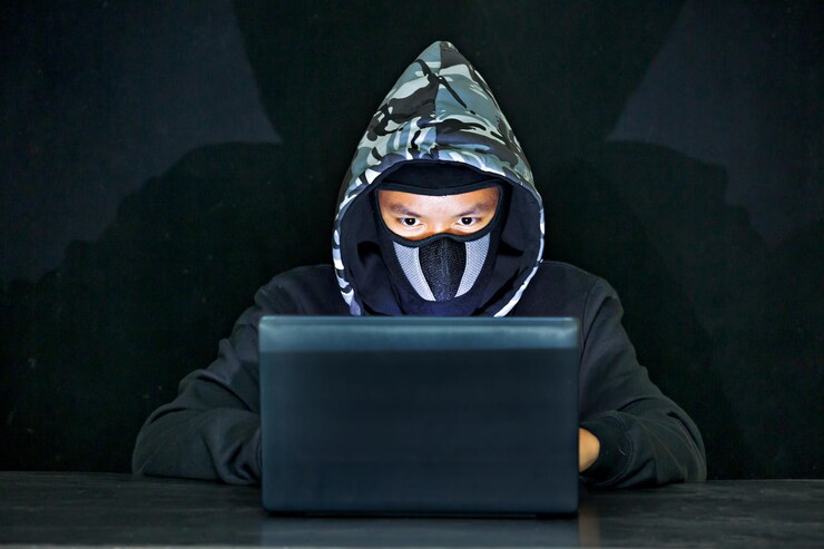 Foto hacker informático usando una computadora portátil en la mesa contra un fondo negro