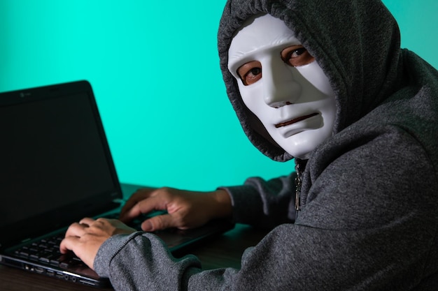 Hacker ladrão na máscara roubando informações pessoais do laptop