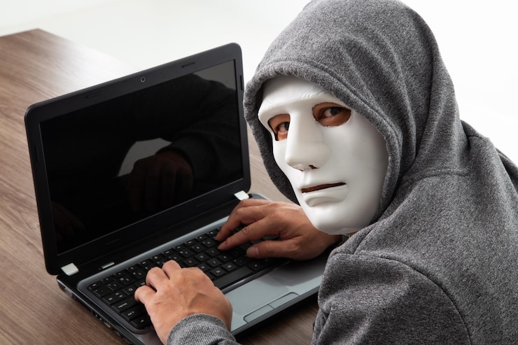 Foto hacker ladrón en máscara robando información personal de la computadora portátil
