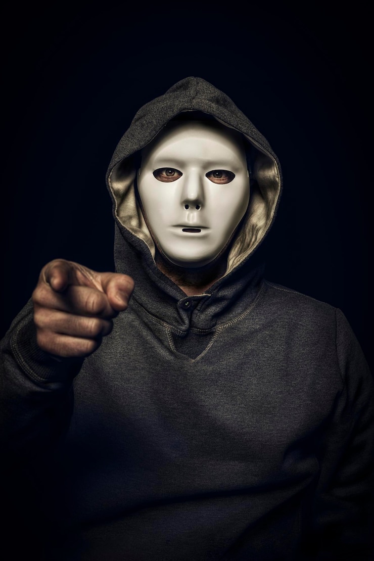 Foto hacker con máscara blanca con la mano apuntando a la cámara