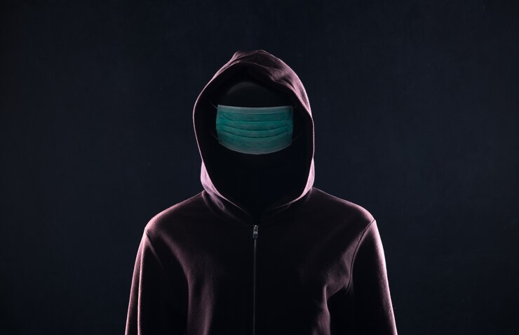 Foto hacker con una máscara médica en el capó