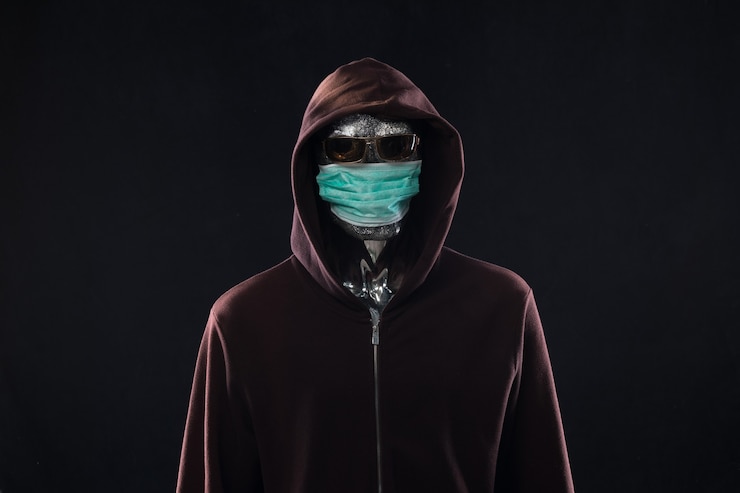 Foto hacker con una máscara médica en el capó