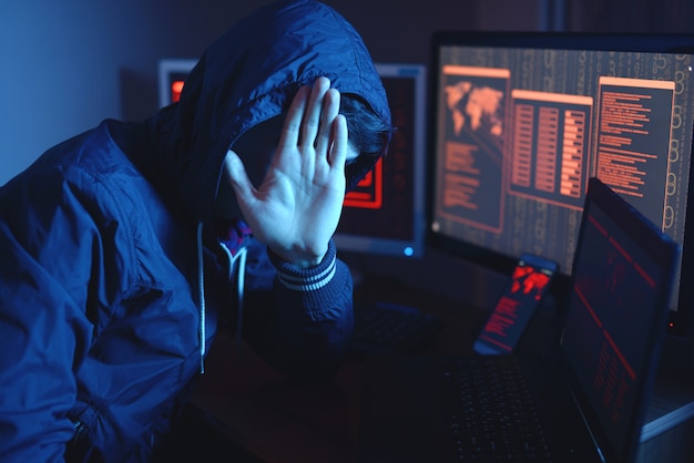 Hacker masculino con capucha atacando una base de datos