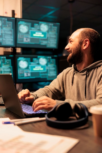 Hacker masculino robando datos informáticos del servidor, usando capucha y haciendo ciberterrorismo con múltiples pantallas. Hackeo de servidores y ataques cibernéticos usando virus para infectar el sistema de red.