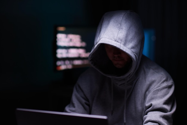 Hacker mit dem Computer Mann mit Kapuze bricht den Zugang, um Informationen zu stehlen und infiziert Computer und Systeme