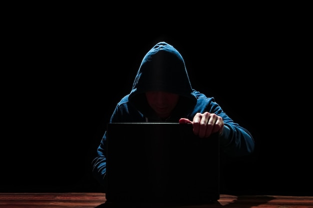 Hacker mit Laptop auf schwarzem Hintergrund