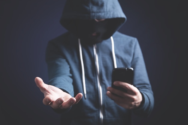 Hacker mit Smartphone. Cyberkriminalität