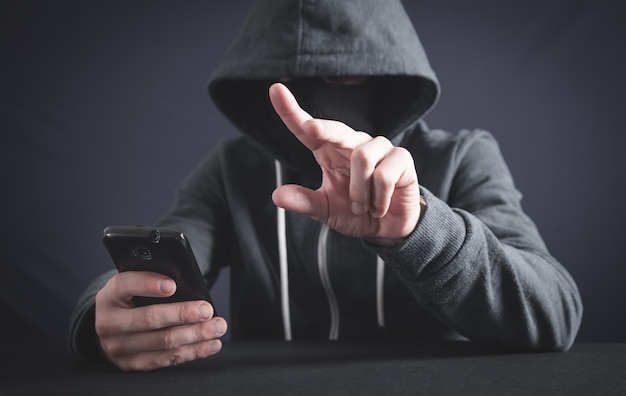 Hacker mit Smartphone und Berühren in leerem Bildschirm. Cyberkriminalität