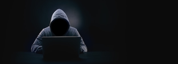 Hacker ohne gesicht in einer kapuze auf dunkelheit