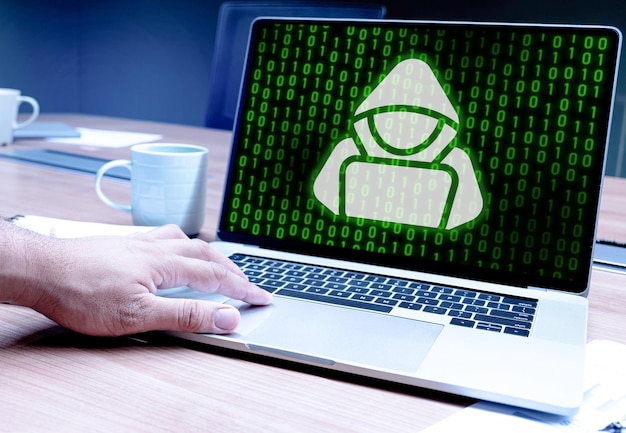 Hacker presionando con la mano el teclado portátil con icono hacker y fondo numérico binario verde en la pantalla