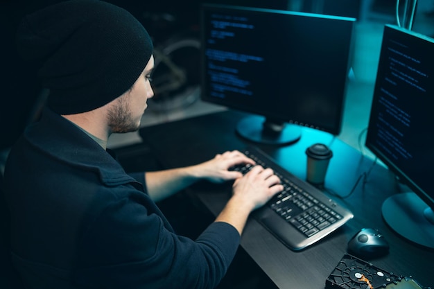 Un hacker con sudadera y gorra intenta hackear un sistema de seguridad