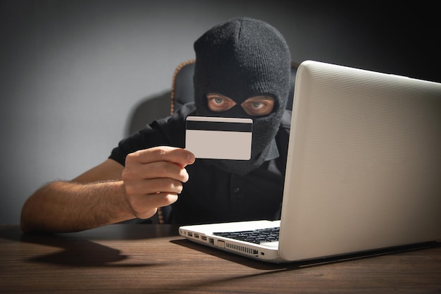 Foto hacker con tarjeta de crédito y computadora portátil delito cibernético